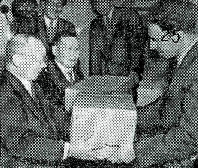 写真:ウシヤコフ船長にリンゴを手渡す坂本町長(左)(昭和33年1月25日の新聞記事から)